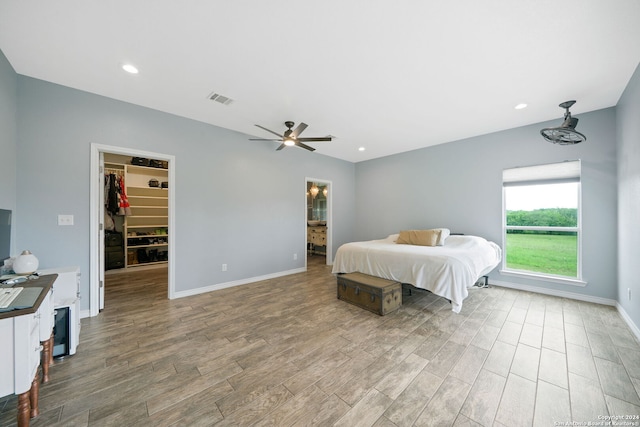 bedroom featuring baseboards, visible vents, a walk in closet, and wood finished floors