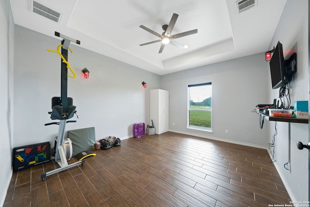 workout room featuring baseboards, visible vents, dark wood-type flooring, and a tray ceiling