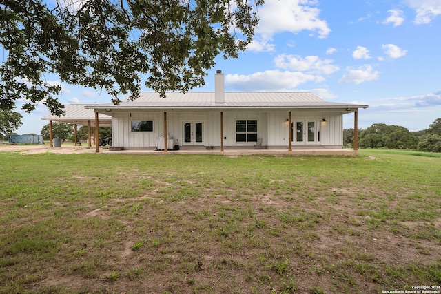 back of property featuring metal roof, french doors, a lawn, board and batten siding, and a chimney