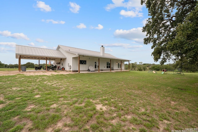 rear view of property with a carport, metal roof, a lawn, and a chimney