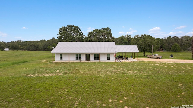 view of front of house with driveway, metal roof, a porch, and a front yard