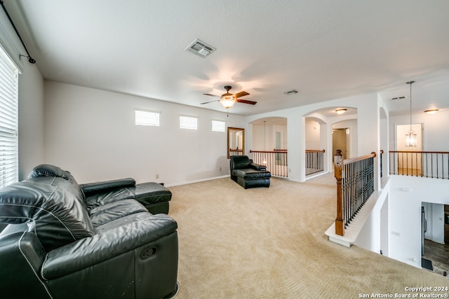 carpeted living room with ceiling fan with notable chandelier and a healthy amount of sunlight