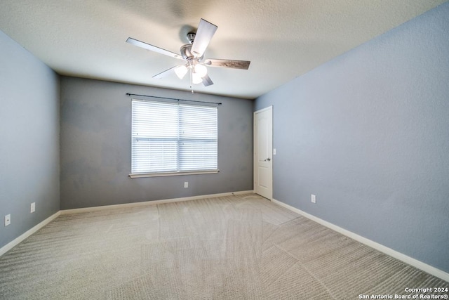 unfurnished room featuring light carpet, ceiling fan, baseboards, and a textured ceiling