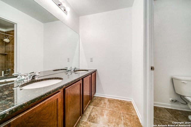 bathroom with tile patterned flooring, toilet, a tile shower, and vanity