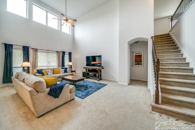 living room with baseboards, arched walkways, a ceiling fan, stairway, and carpet flooring