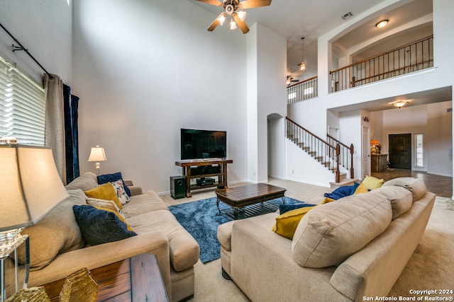 carpeted living room with ceiling fan and a high ceiling