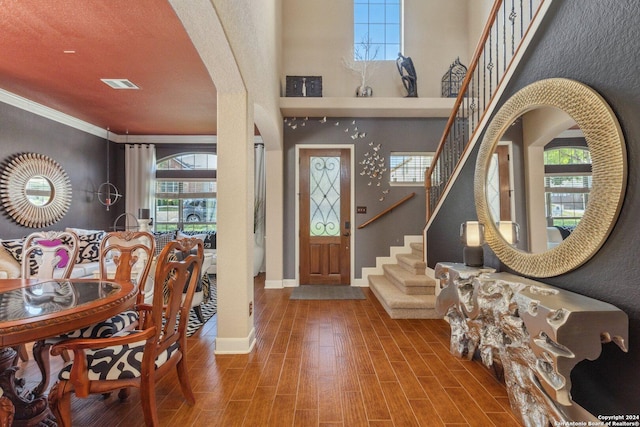 foyer featuring arched walkways, plenty of natural light, stairs, and wood tiled floor