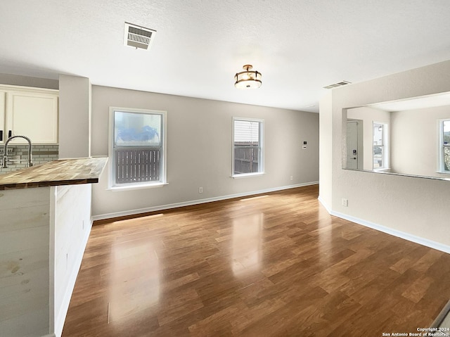 unfurnished living room with wood finished floors, a sink, and visible vents