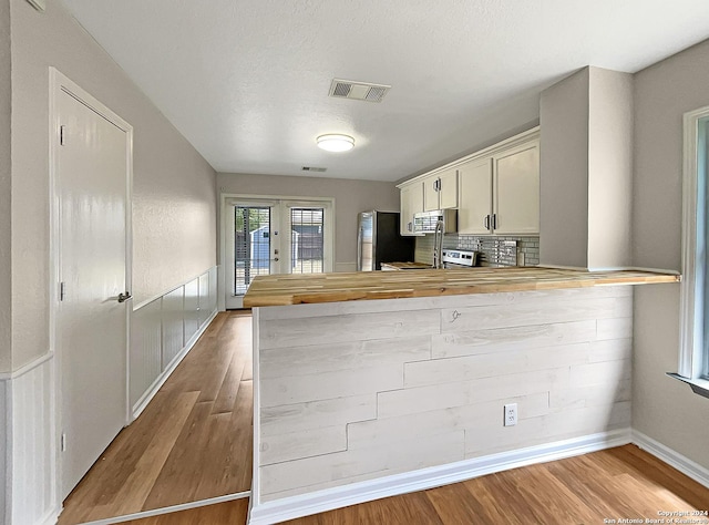 kitchen featuring french doors, visible vents, wooden counters, appliances with stainless steel finishes, and wood finished floors