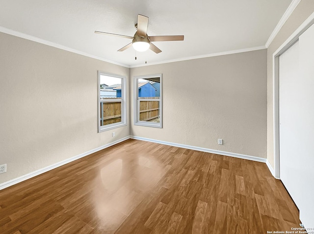 unfurnished room featuring crown molding, baseboards, and wood finished floors