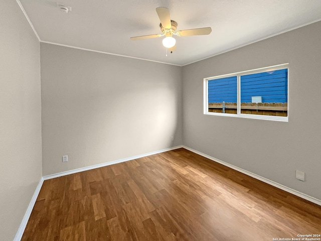 spare room with a ceiling fan, crown molding, baseboards, and wood finished floors