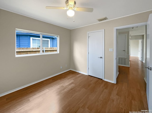 unfurnished bedroom with a ceiling fan, wood finished floors, visible vents, and baseboards