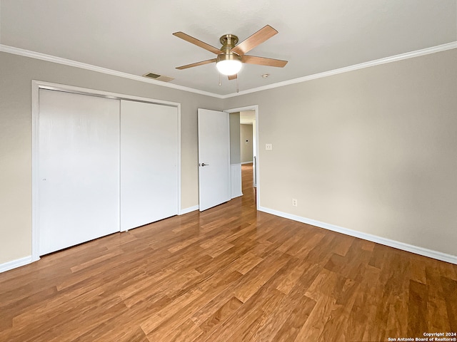 unfurnished bedroom with ceiling fan, ornamental molding, a closet, and wood-type flooring