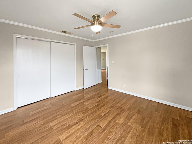 unfurnished bedroom featuring baseboards, visible vents, ornamental molding, wood finished floors, and a closet