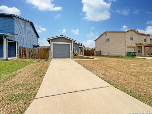 view of front of home with an attached garage, concrete driveway, a front yard, and fence