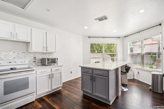 kitchen with backsplash, a kitchen island, dark hardwood / wood-style flooring, gray cabinetry, and white range with electric cooktop