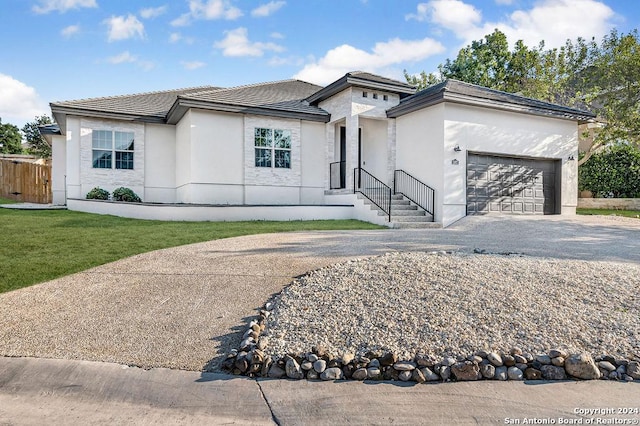 prairie-style home with a garage, a tile roof, driveway, and stucco siding