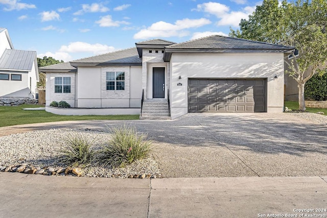 view of front of house featuring a garage, concrete driveway, a tile roof, and stucco siding