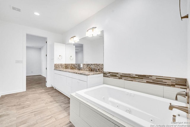 bathroom featuring double vanity, baseboards, visible vents, wood finished floors, and a whirlpool tub