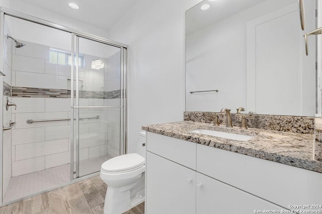 bathroom featuring toilet, a shower stall, recessed lighting, and vanity