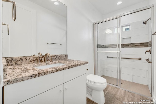 bathroom featuring toilet, a stall shower, wood finished floors, and vanity