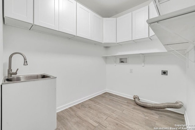 clothes washing area with cabinet space, light wood-style flooring, hookup for an electric dryer, a sink, and baseboards