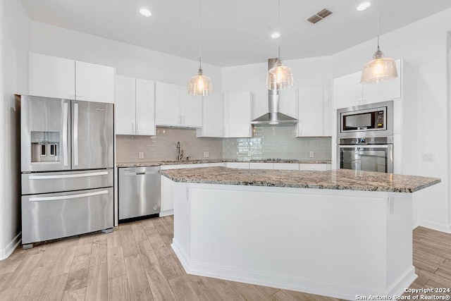 kitchen with appliances with stainless steel finishes, backsplash, white cabinetry, and light wood-style flooring