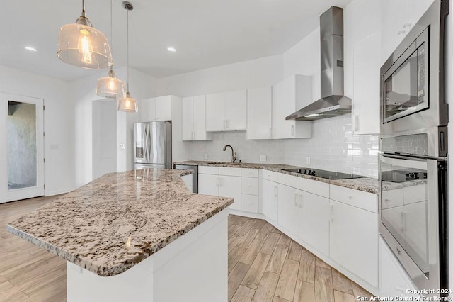 kitchen with a kitchen island, a sink, appliances with stainless steel finishes, decorative backsplash, and wall chimney exhaust hood