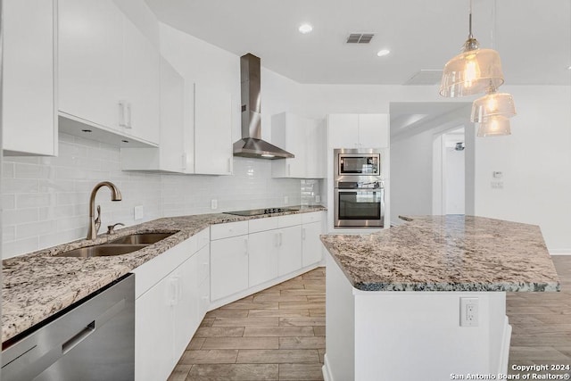 kitchen with wood finish floors, a sink, wall chimney range hood, appliances with stainless steel finishes, and backsplash