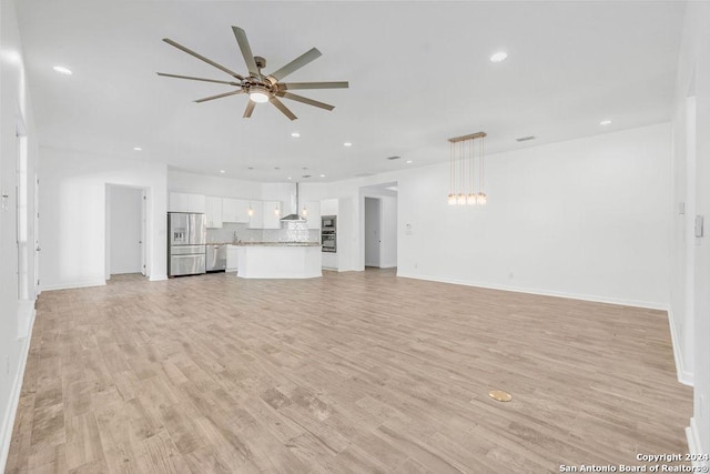 unfurnished living room featuring ceiling fan, recessed lighting, baseboards, and light wood-style floors