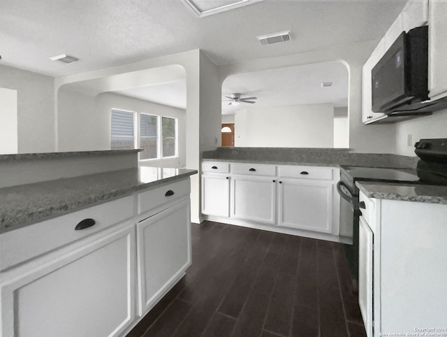 kitchen with dark stone counters, white cabinetry, kitchen peninsula, ceiling fan, and dark wood-type flooring