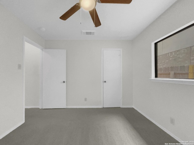 carpeted empty room with a ceiling fan, visible vents, and baseboards