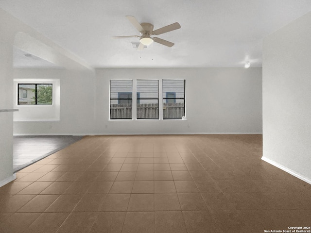 tiled spare room featuring a ceiling fan and baseboards