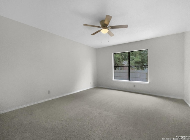 carpeted empty room with ceiling fan and baseboards