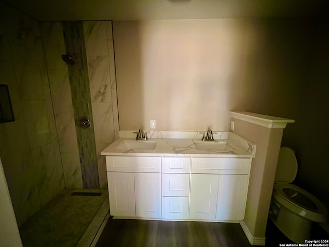 bathroom featuring vanity, toilet, a tile shower, and hardwood / wood-style floors