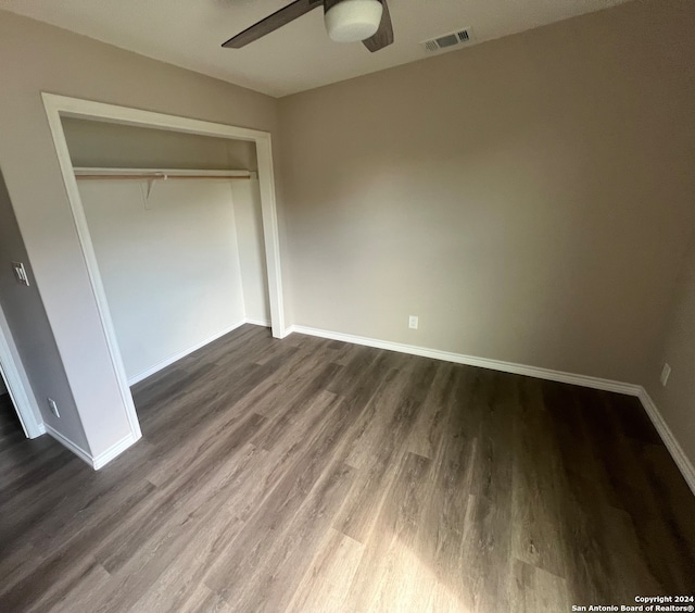 unfurnished bedroom featuring dark wood-type flooring, ceiling fan, and a closet