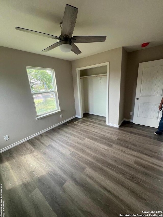 unfurnished bedroom with dark wood-type flooring, ceiling fan, and a closet