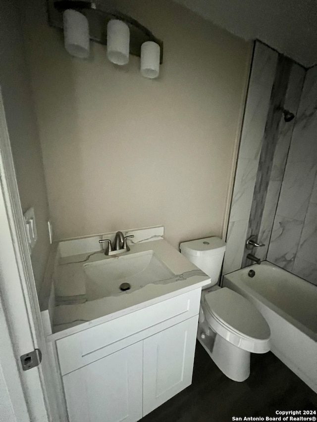 full bathroom featuring tiled shower / bath, vanity, and toilet