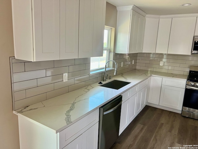 kitchen with white cabinets, backsplash, appliances with stainless steel finishes, dark hardwood / wood-style flooring, and sink