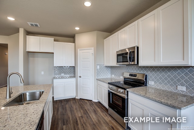 kitchen with visible vents, appliances with stainless steel finishes, light stone countertops, white cabinetry, and a sink