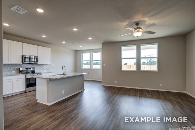 kitchen with a kitchen island with sink, stainless steel appliances, a sink, visible vents, and white cabinetry