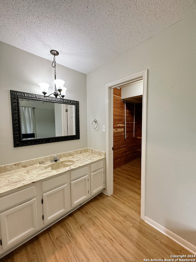 bathroom featuring a textured ceiling, hardwood / wood-style floors, an inviting chandelier, and vanity