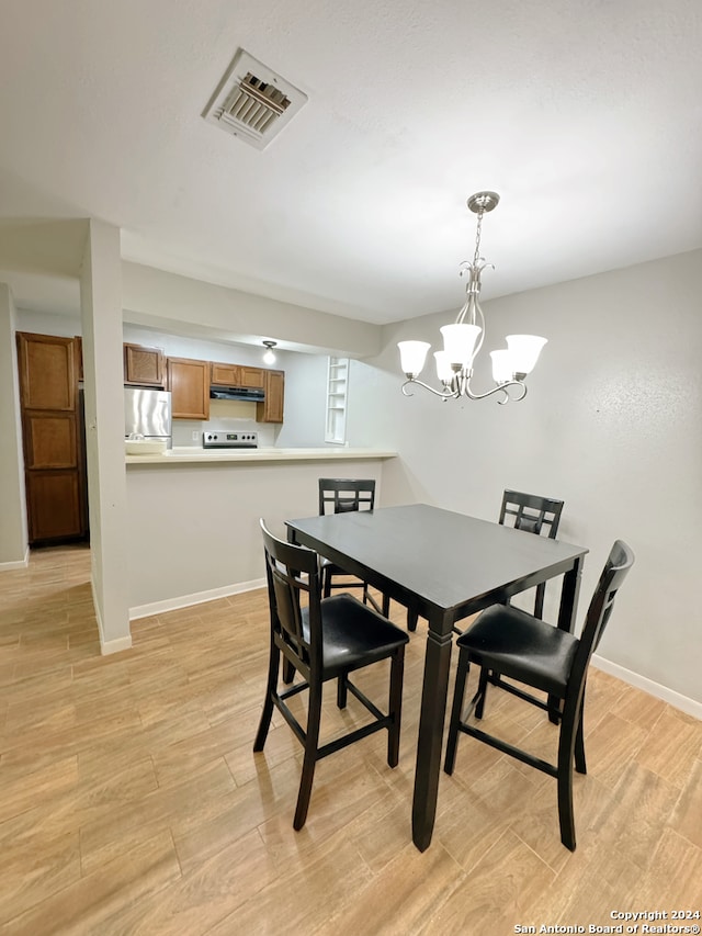 dining area featuring light hardwood / wood-style flooring and an inviting chandelier