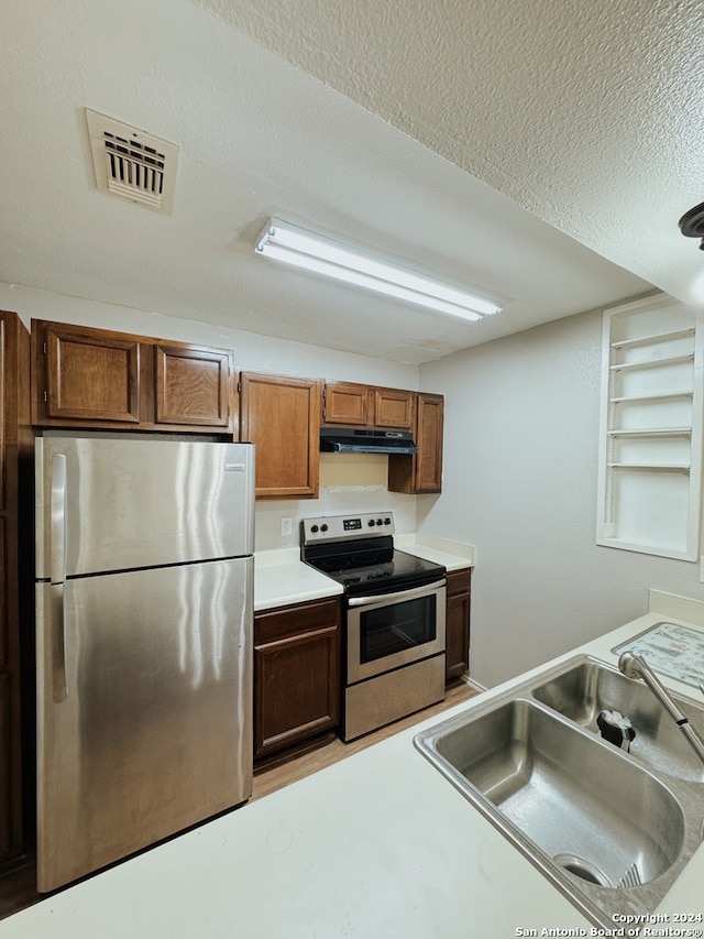 kitchen with appliances with stainless steel finishes, sink, and a textured ceiling