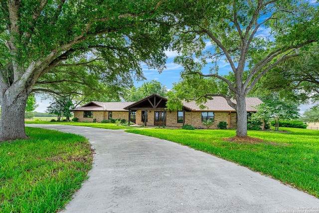 ranch-style house with brick siding, curved driveway, and a front lawn