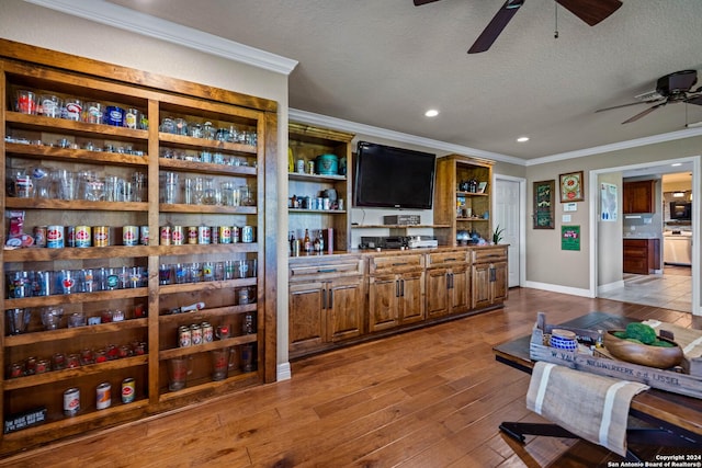 interior space with a textured ceiling, a ceiling fan, ornamental molding, and wood finished floors