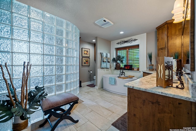 bathroom featuring tile patterned floors, a bathing tub, a textured ceiling, vanity, and toilet