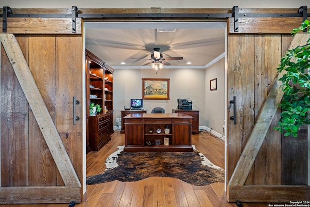office area featuring ornamental molding, baseboards, light wood finished floors, and a barn door