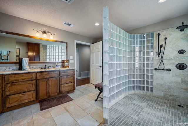 bathroom featuring tile patterned floors, a textured ceiling, vanity, and tiled shower