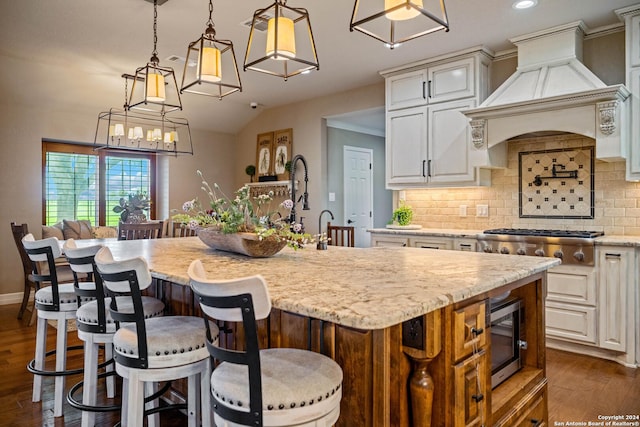 kitchen with appliances with stainless steel finishes, dark wood-style floors, a center island with sink, custom range hood, and backsplash